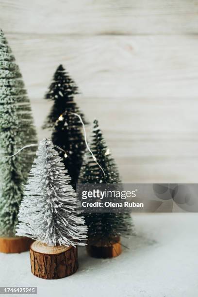 christmas trees on stumps with led string garland against wooden wall. - led stumps stock pictures, royalty-free photos & images
