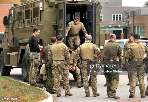 Lewiston, ME New Hampshire State Police meet behind an armored vehicle as they wear camouflage at Lewiston High School which is serving as a staging...