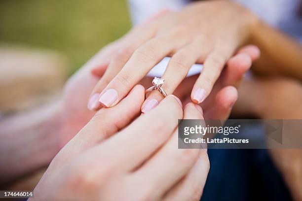 female and male hands slipping on engagment ring - life ring stockfoto's en -beelden