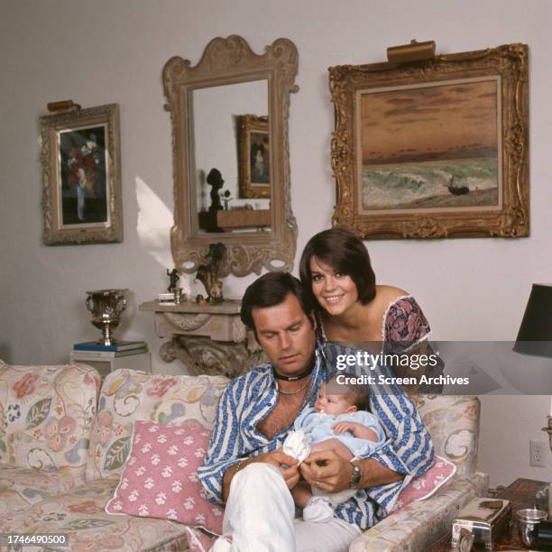 Robert Wagner holds baby daughter Courtney as Natalie Wood stands behind them posing at their home 1974.