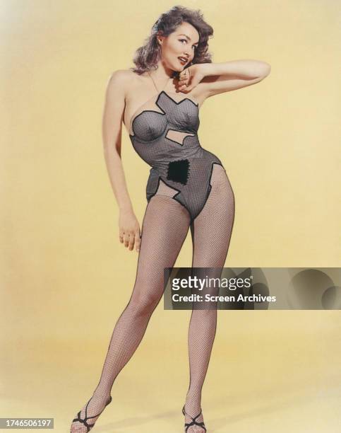 Julie Newmar poses for publicity pin up portrait wearing fishnet stockings and costume circa 1960.