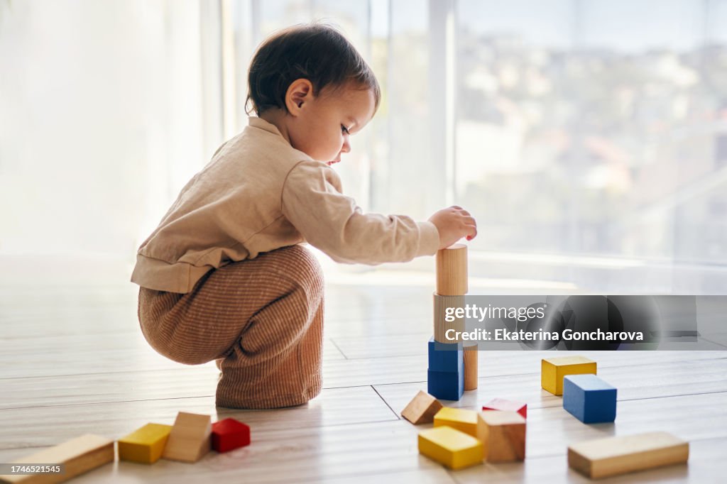 A girl is playing wooden cubes on the floor