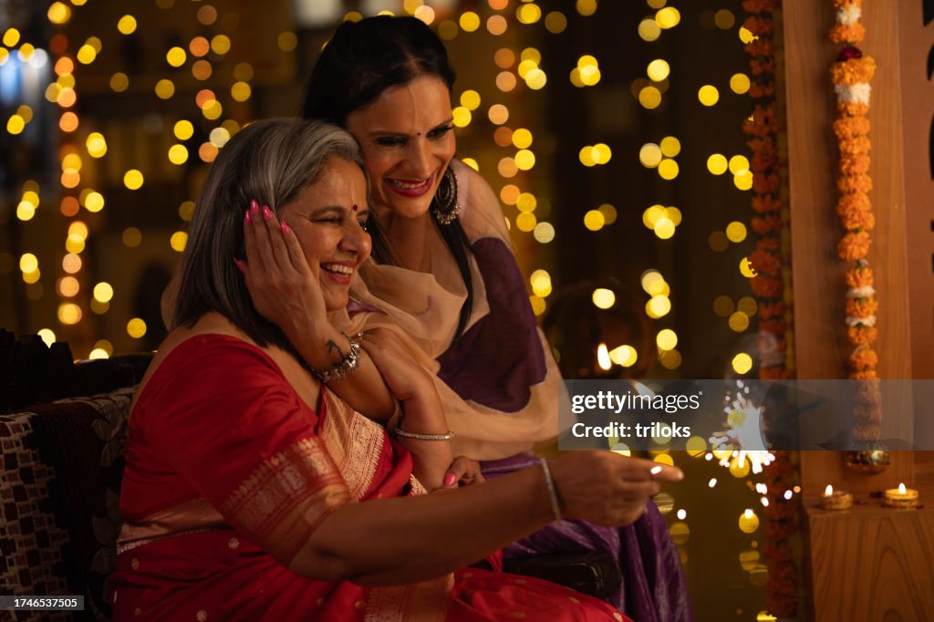 Mother and daughter playing with sparklers at home
