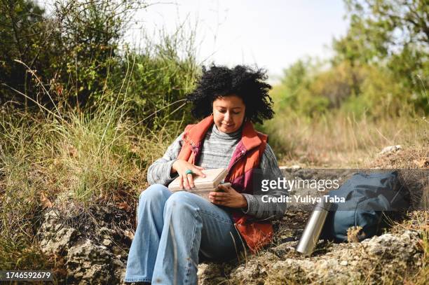 multirassische mittelerwachsene frau, die eine pause beim essen in der natur macht. - wildnisgebiets name stock-fotos und bilder