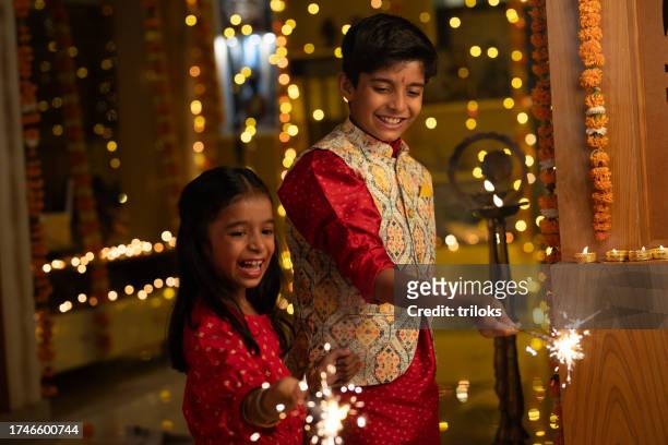 fratelli felici che giocano con le stelle filanti a casa durante il diwali - bhai dooj festival celebration foto e immagini stock