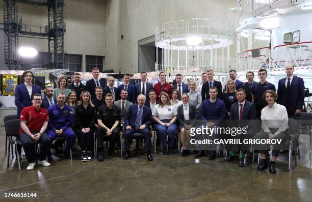 This pool photograph distributed by Russian state owned agency Sputnik shows Russia's President Vladimir Putin posing with young scientists during a...