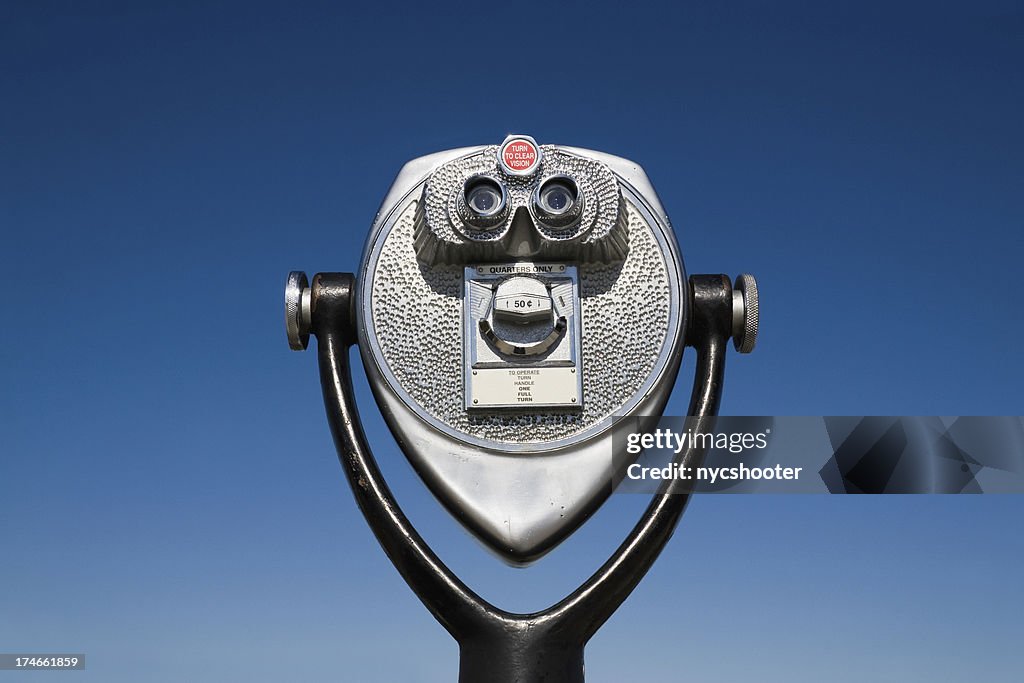 Coin Operated Binoculars set against blue sky background