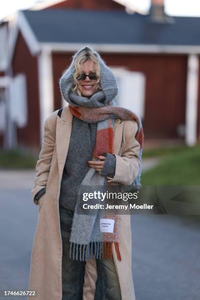 Katarina Krebs seen wearing a black sunglasses, Copenhagen Studios colorful checked wool scarf, grey wool knit pullover, beige corduroy long coat,...