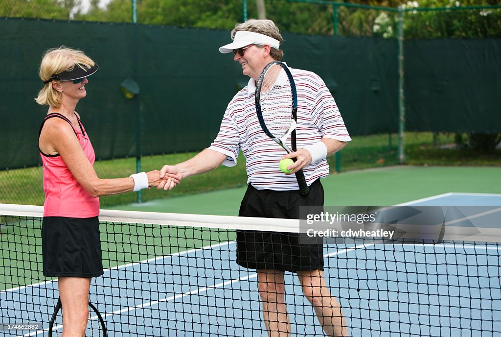 Senior couple shaking hands after tennis match