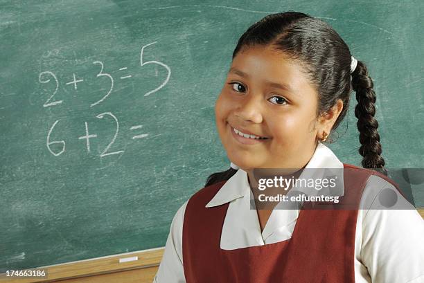 schoolgirl in a uniform in front of the chalkboard - hoofd schuin stockfoto's en -beelden