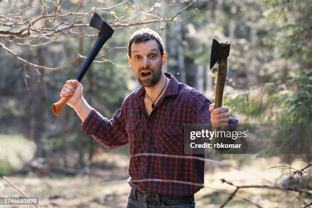 furious man with two axes in the forest - axe stock pictures, royalty-free photos & images
