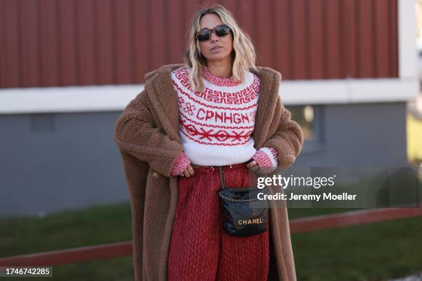 Karin Teigl seen wearing a black sunglasses, Copenhagen Studios white / red logo pattern knit wool pullover, brown fluffy long teddy coat, red print...