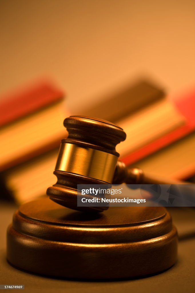 Wooden gavel and law books at the background