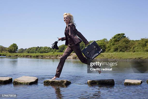 a businesswoman walking on the stepping stones successfully  - stepping stones stockfoto's en -beelden