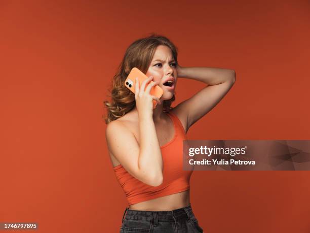 a young woman is talking emotionally on the phone, gesticulating - augen verdrehen stock-fotos und bilder