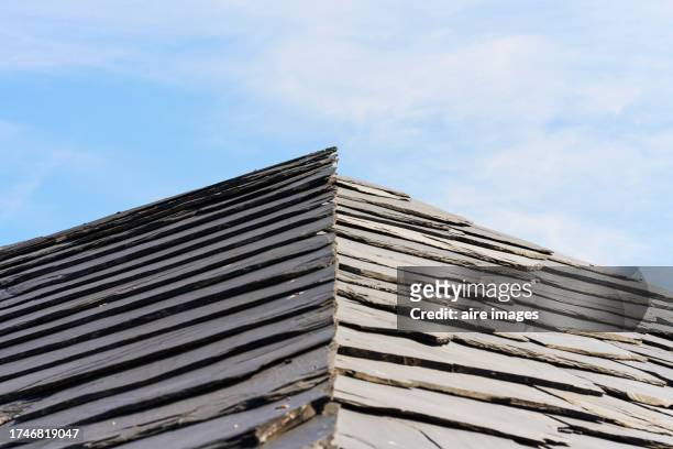front view of a slate roof on an old structure with the sky in the background on a sunny day - sunny leon stockfoto's en -beelden