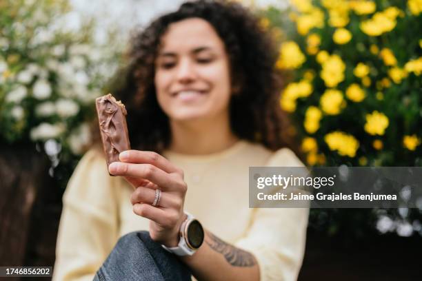 nahaufnahme einer frau, die schokoriegel in den händen hält - riegel stock-fotos und bilder