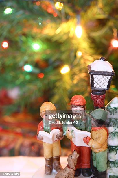 christmas carolers figurines over a christmas background - carol singer stock pictures, royalty-free photos & images