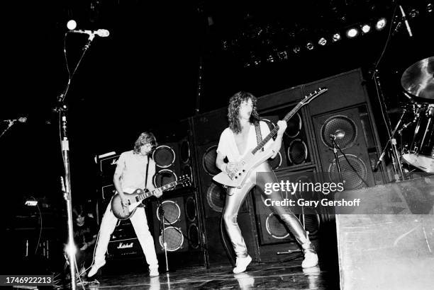 View of English Rock musicians Steve Clark , left, on electric guitar, and Rick Savage, on bass guitar, both of the group Def Leppard, as they...