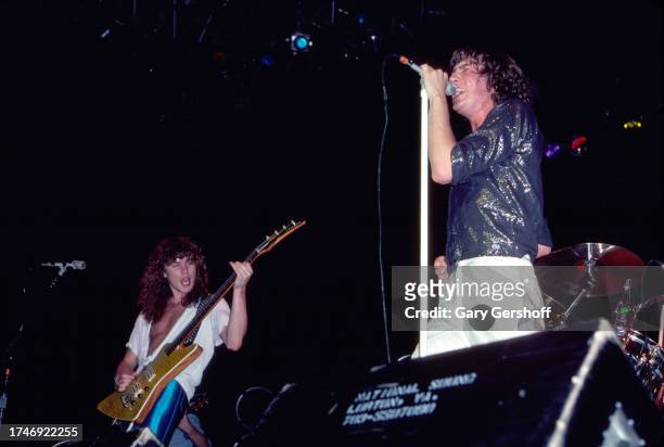 View of English musicians Rick Savage , on bass guitar, and singer Joe Elliott, both of the group Def Leppard, as they perform onstage at Nassau...