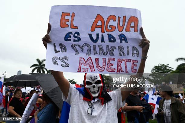 Demonstrator holds a sign reading "Water is life, Mining is death" during a protest against the government contract with Canadian mining company...