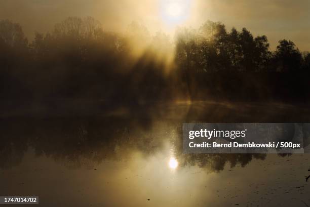 scenic view of lake against sky at sunset - bernd dembkowski stock-fotos und bilder