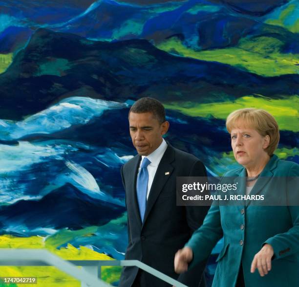 Democratic presidential candidate Barack Obama walks with German Chancellor Angela Merkel as she looks up at the media waiting for a photo...