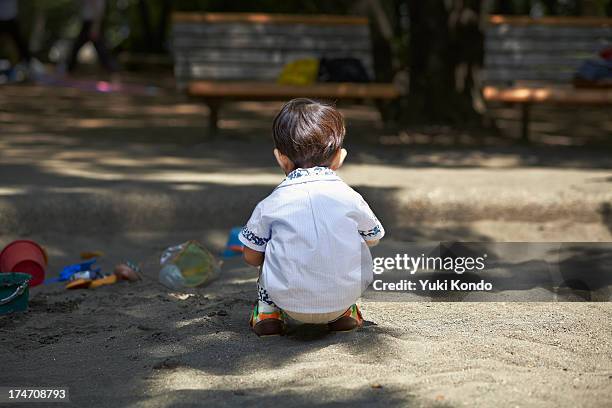 the boy who plays in a sandbox. - sandkasten stock-fotos und bilder