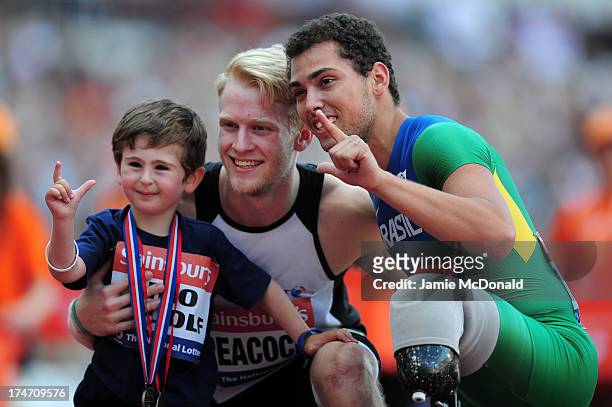 Alan Oliveira of Brazil and Jonnie Peacock of Great Britain pose with 5 year old Rio Woolf after winning the Mens T43/44 100mduring day three of the...