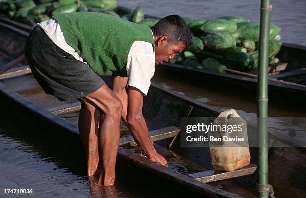 Local loads up his boat with papaya and other fruits on the Mekong River, near the picturesque village of Sangkhom in Northeast Thailand. The Mekong,...