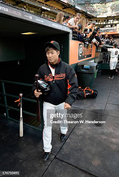 Kensuke Tanaka of the San Francisco Giants walks into the dugout with his bats and glove before the start of his game against the Chicago Cubs at...