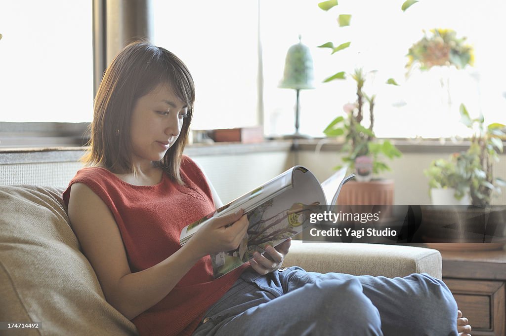 Woman reading a magazine while sitting on a couch