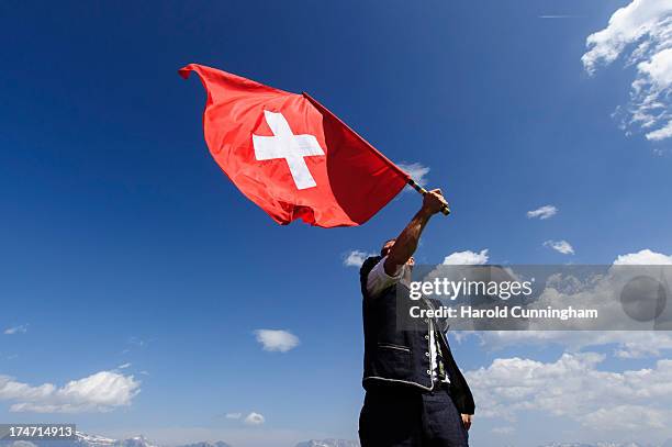 Man throws a Swiss flag on July 28, 2013 in Nendaz, Switzerland. About 150 Alphorn blowers performed together on the last day of the international...
