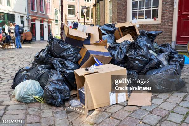 pile of garbage at curbside with cardboard boxes and bags, no people around, front view - vuilniszak stockfoto's en -beelden