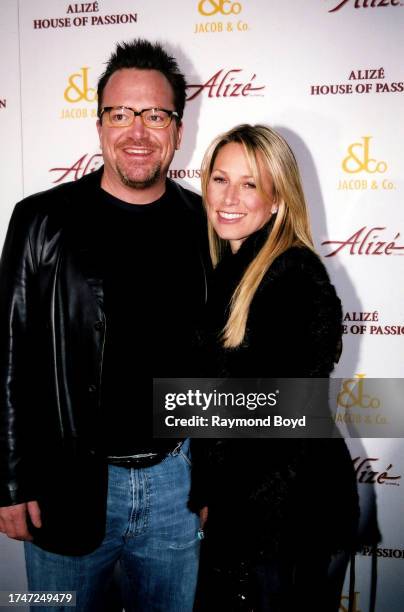 Comedian and actor Tom Arnold poses for photos with Ashley Groussman on the red carpet during the 'Alize House of Passion' event at the Playboy...