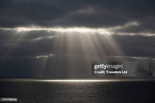 beams of sunlight over water - storm cloud ストックフォトと画像