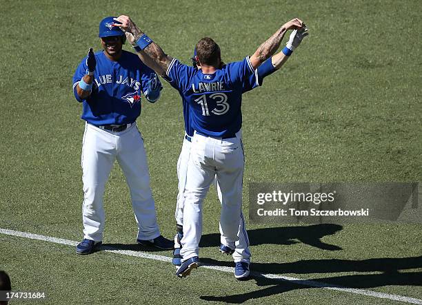 Colby Rasmus of the Toronto Blue Jays is congratulated by Brett Lawrie and Edwin Encarnacion after a game-winning RBI single in the ninth inning...