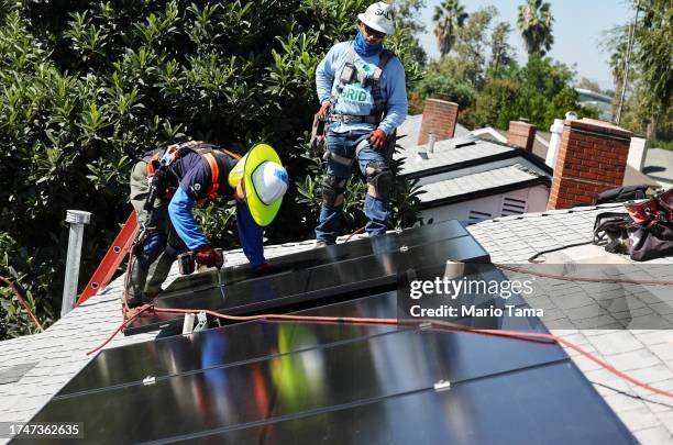 Alternatives employees Tony Chang and Sal Miranda install no-cost solar panels on the rooftop of a low-income household on October 19, 2023 in...