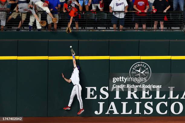 Evan Carter of the Texas Rangers attempts to catch Jose Altuve of the Houston Astros three run home run during the ninth inning in Game Five of the...