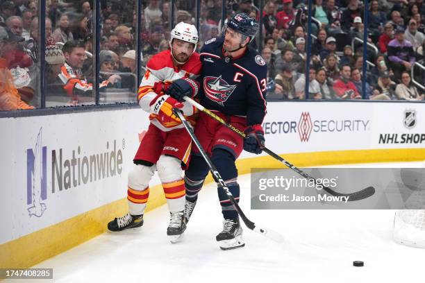 Boone Jenner of the Columbus Blue Jackets hits Rasmus Andersson of the Calgary Flames during the during the second period at Nationwide Arena on...