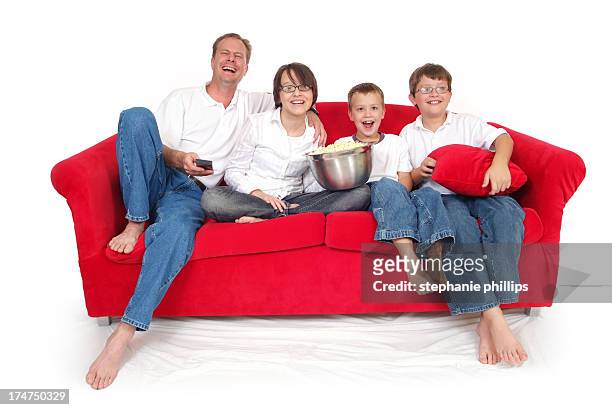 family of four sitting on red couch watching a movie - family white background stock pictures, royalty-free photos & images
