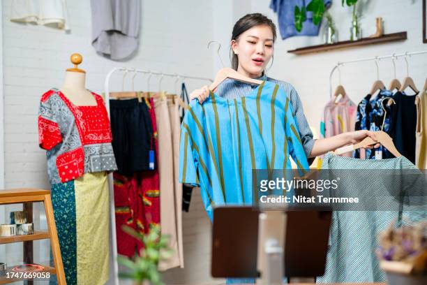 increasing your sell with live-stream shopping events in social media platforms.  a female boutique store owner on live-streaming via a tablet computer and presenting fashion clothing products to her customers. - personalised communication stock-fotos und bilder