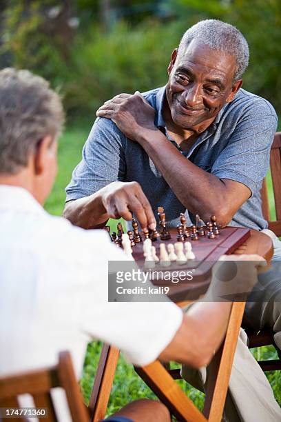 senior men playing chess in park - senior playing chess stock pictures, royalty-free photos & images