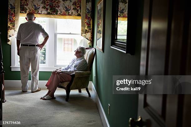 pensif couple âgé regardant par la fenêtre - chaise de dos photos et images de collection