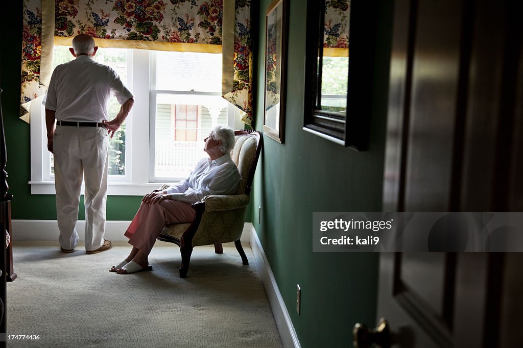 Pensive senior couple looking out window