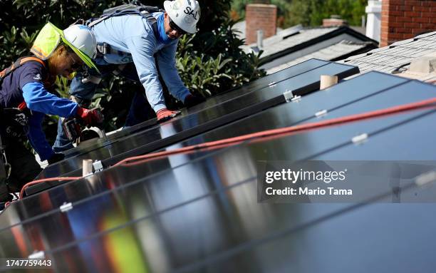 Alternatives employees Tony Chang and Sal Miranda install no-cost solar panels on the rooftop of a low-income household on October 19, 2023 in...