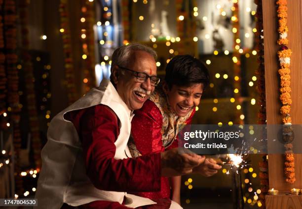 grandfather and grandson playing with sparkler at home - india celebrates diwali festival stock pictures, royalty-free photos & images