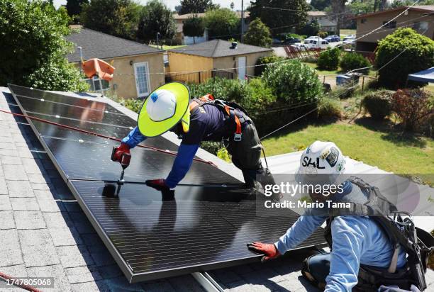 Alternatives employees Sal Miranda and Tony Chang install no-cost solar panels on the rooftop of a low-income household on October 19, 2023 in...