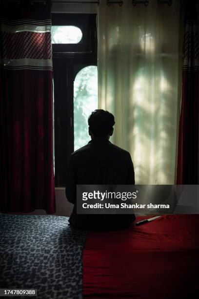 silhouette of rear view of a murderer sitting on bed. - víctima de asesinato fotografías e imágenes de stock