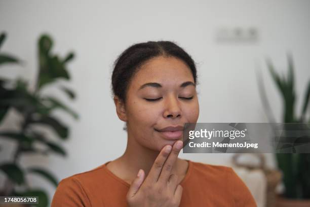 stress relief techniques. happy calm african american woman using eft tapping to relieve stress and anxiety, touching face with fingertips. emotional freedom technique - tapping points stockfoto's en -beelden